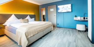 ein Schlafzimmer mit einem großen Bett und einer blauen Wand in der Unterkunft Hotel Das Augustin in Sankt Augustin