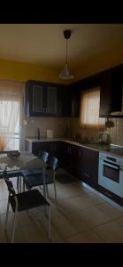 een keuken met zwarte kasten en een tafel en stoelen bij Vicky's house in Olympiada