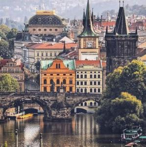 a city with a bridge over a river and buildings at Hotel Karlin in Prague