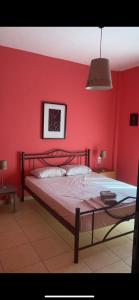 a bedroom with a red wall with a bed at Vicky's house in Olympiada