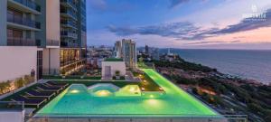 una piscina al lado de un edificio con el océano en Andromeda Seaview Condo Near Beach, en Pattaya South