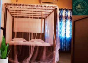 a room with a bed with a curtain and a window at Neembuva Resort in Pahala Maragahawewa