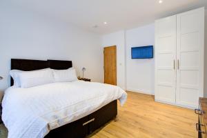 a bedroom with a large bed with white walls and wooden floors at Large 4 Bedroom All Ensuite Bathroom in Brentwood with Sky TV & Lots of Parking in Brentwood