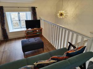 a living room with a couch and a tv at The Old Fire Station at Colerne in Chippenham