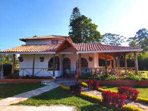 una pequeña casa blanca con techo rojo en HERMOSA CABAÑA VILLA JULIA MESA DE LOS SANTOS, en Piedecuesta