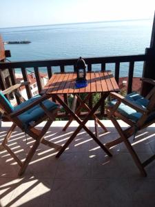 a wooden table and chair on a balcony overlooking the ocean at Irida Maria in Agios Ioannis Pelio