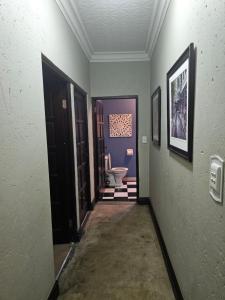 a hallway with a toilet in a room with purple walls at Castle Home in Centurion