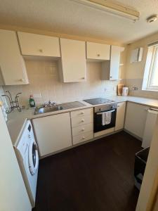 cocina con armarios blancos, fregadero y lavavajillas en One bedroom flat and spare bed, en Bristol