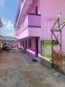 un edificio rosa y morado con aparcamiento en Hotel PNR'S Paradise en Ooty