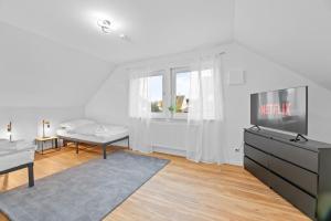 a white living room with a tv and a table at W02 Business Apartment für Teams in Wendlingen am Neckar