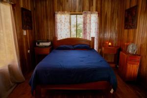 - une chambre avec un lit bleu et une fenêtre dans l'établissement Rancho Costafalo Eco-Tourism Farm, à Quebrada Grande