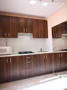 a kitchen with wooden cabinets and a microwave at Квартира на Оболоні in Kyiv