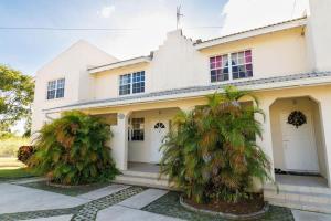 a white house with two palm trees in front of it at 2 Bedroom Apartment at Maynards in Saint Peter