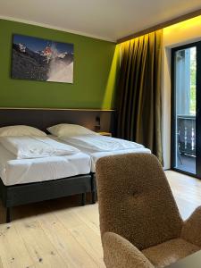 a bedroom with a bed and a chair next to a window at Hotel Simader in Bad Gastein