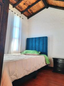 1 cama con cabecero azul en una habitación en Hostal Oycate, en Oicatá