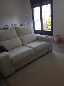 um sofá branco numa sala de estar com uma janela em La casita de la abuela em Moaña