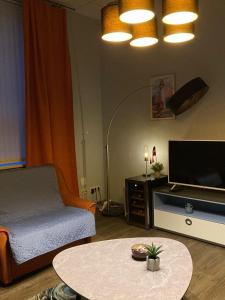 a living room with a couch and a tv and a table at Pumpura apartamenti ***** in Talsi