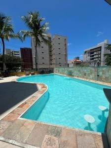 卡貝德盧的住宿－Flat na Praia de Intermares，一座种植了棕榈树和建筑的大型蓝色游泳池
