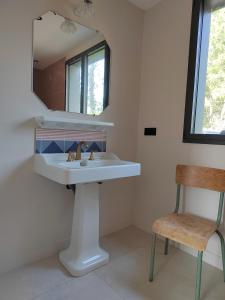 a bathroom with a sink and a mirror and a chair at Joyau au cœur de la forêt in La Guérinière