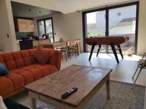 a living room with a couch and a table and a piano at Joyau au cœur de la forêt in La Guérinière +3 photos