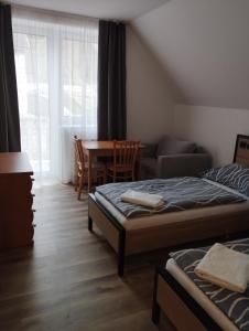 sypialnia z 2 łóżkami, stołem i kanapą w obiekcie Penzion Kormorán w mieście Vranov nad Dyjí