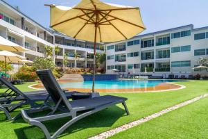 uma piscina com duas espreguiçadeiras e um guarda-sol em Seaview Apartments - Karon Beach em Ka Rorn