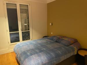 ein Schlafzimmer mit einem Bett mit blauer Decke und einem Fenster in der Unterkunft 70m2 Cosy Apartment Daguerre in Paris