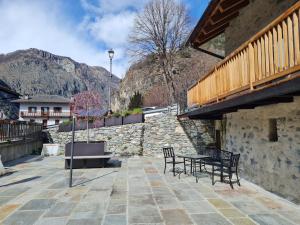 a patio with a table and chairs and a stone wall at La corte Antey Maison De Emilie in Antey-Saint-André