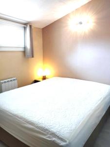 um quarto com uma grande cama branca e uma janela em Appartement T2 Argelès plage em Argelès-sur-Mer