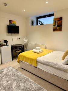 a bedroom with a bed with a yellow blanket and a desk at Cute and Comfy Studio in King’s Cross in London