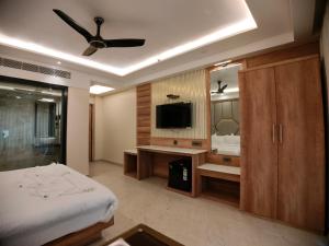 een slaapkamer met een bed en een televisie en een spiegel bij AGM GRAND HOTEL & Spa in Digha