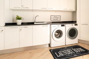 eine Küche mit weißen Schränken und einer Waschmaschine und einem Trockner in der Unterkunft Bella Vista (Heated Pool & Private Parking) in Arco da Calheta