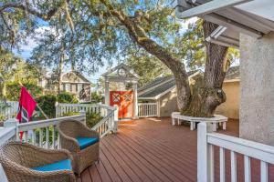 a deck with chairs and a tree on a house at The Coral Door Beach House - 4315 Fourth Street in Saint Simons Island