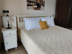 a bed with white pillows and a night stand with a lamp at XΡΗΣΤΟΣ house in Ioannina