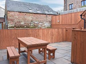 a wooden fence with a picnic table and two benches at Doomgate House - Uk45055 in Appleby