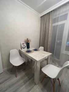 una mesa blanca con dos sillas y un jarrón en ella en Nurly Zhol apartment, en Promyshlennyy
