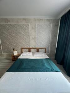 1 dormitorio con 1 cama grande y cortinas azules en Nurly Zhol apartment, en Promyshlennyy