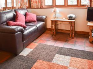 a living room with a leather couch and a television at Uk46715 - The Coach House in Plumstead
