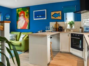 Blue Waters في ويماوث: مطبخ بجدران زرقاء وأريكة خضراء