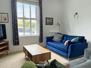a living room with a blue couch and a coffee table at Poppy Cottage in Eryholme