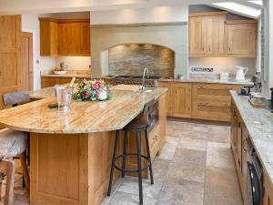 a large kitchen with wooden cabinets and a large island at Elizabeth Cottage in Glossop