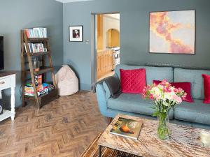 a living room with a blue couch and a table at Elizabeth Cottage in Glossop