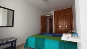 Schlafzimmer mit einem Bett, einem Tisch und einem Spiegel in der Unterkunft Apartamento en Portmán in Portman