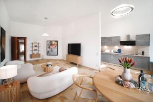 a living room with a table and white chairs at LOEWENHERZ HOMES Luxury Apartment - Stadt- und Seenähe - fellnasenfreundlich - lichtdurchflutet in Stephanskirchen