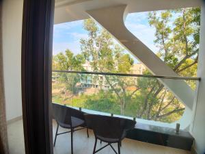 een kamer met een groot raam en een tafel en stoelen bij AGM GRAND HOTEL & Spa in Digha