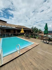 una gran piscina azul en una terraza con mesas y sombrillas en Pousada Inconfidência Mineira en Ouro Preto