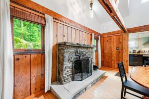 a living room with a stone fireplace and a table at Pet Friendly Creekside Cabin At Darlington in Ligonier
