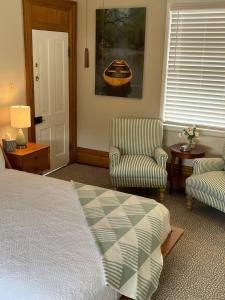 a bedroom with a bed and two chairs and a painting at Large, Bright Suite Kitchenette in Ligonier