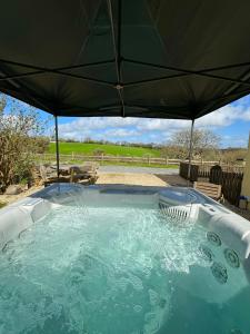 a hot tub with an umbrella in a yard at Meadowsweet Cottage Jacuzzi Edition in Saundersfoot
