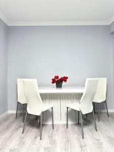 three chairs and a table with a vase of red flowers at Guest House Gayane in Gyumri